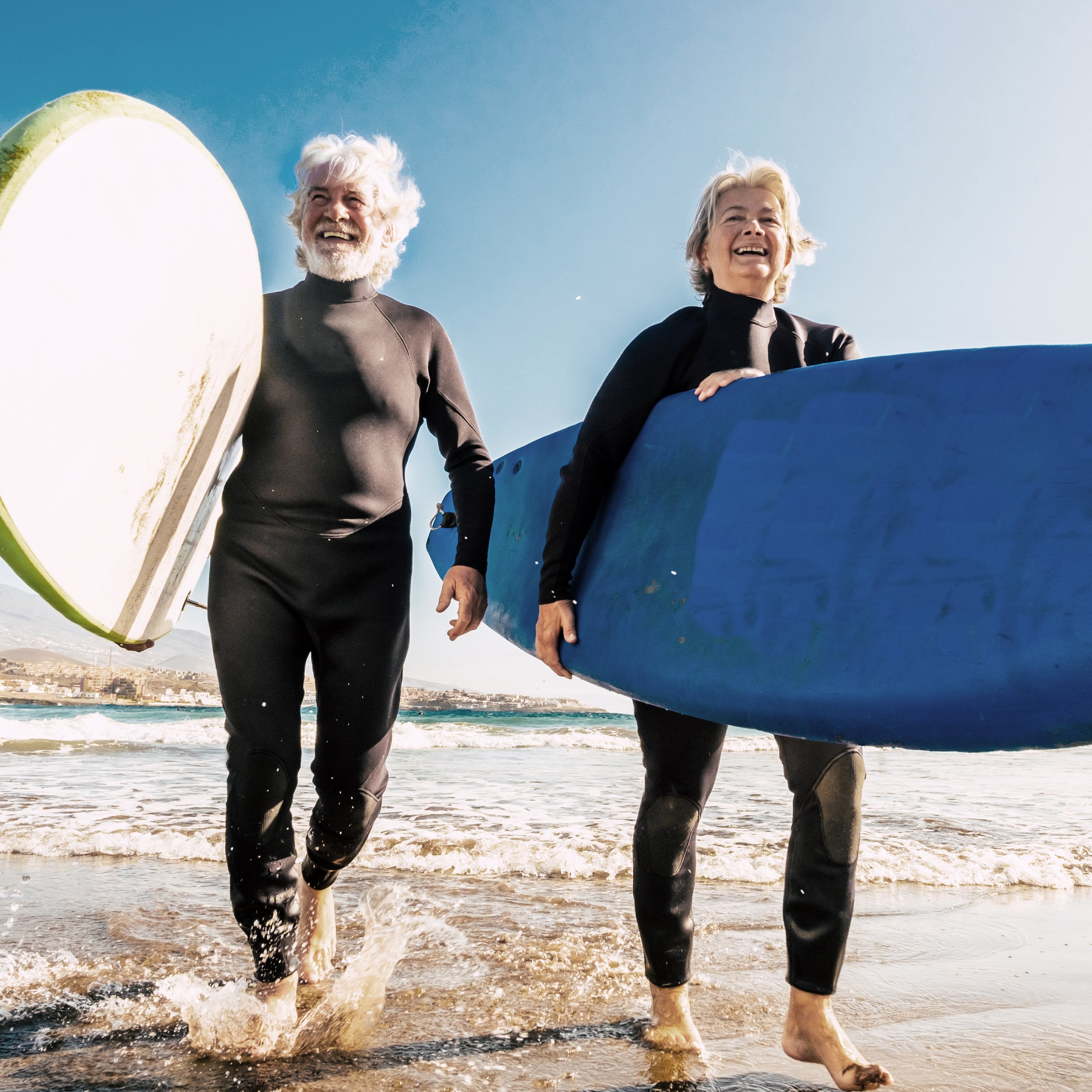 Two elderly people with surfboards by the sea